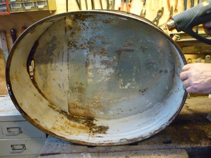 Een trommel ter restauratie wordt ontdaan van de afgebladderde verflaag.